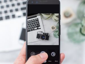 Hand holding phone to photograph flatlay