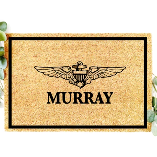 NAVAL AVIATOR WINGS WITH CUSTOM LAST NAME CENTERED UNDER IMAGE. BLACK BORDER AROUND EDGE OF DOORMATE. BORDER 1.5 IINCHES ALL THE WAY AROUND ONE INCH BETWEEN EDGE OF MAT AND BORDER
