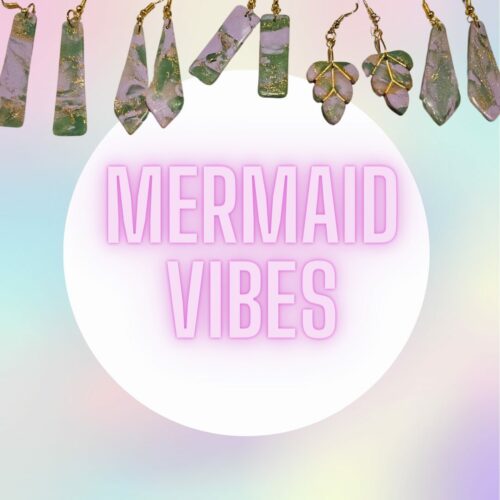 Dangle earrings on a rainbow background with text stating "mermaid vibes"