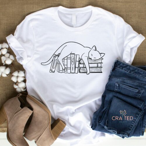 Bella and Canvas Unisex Tee featuring a paws and print doodle outline of sleeping cat + book stack.