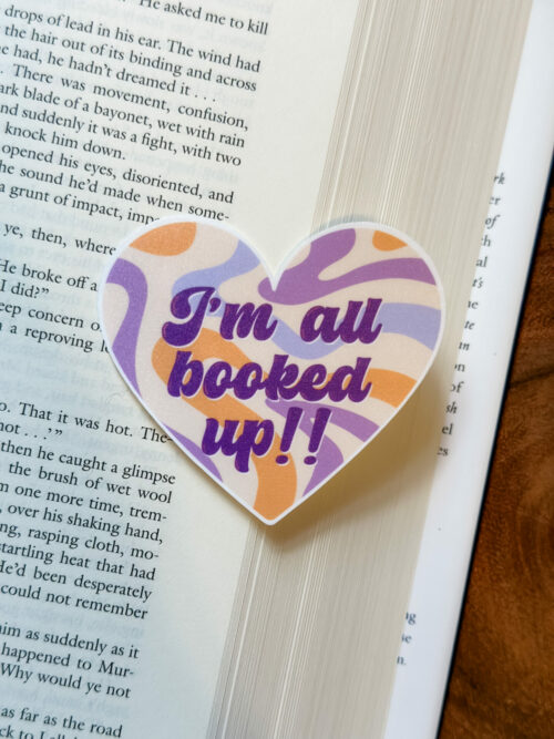 Purple, yellow, and beige retro pattern heart sticker with the saying, “I’m all booked up” on it